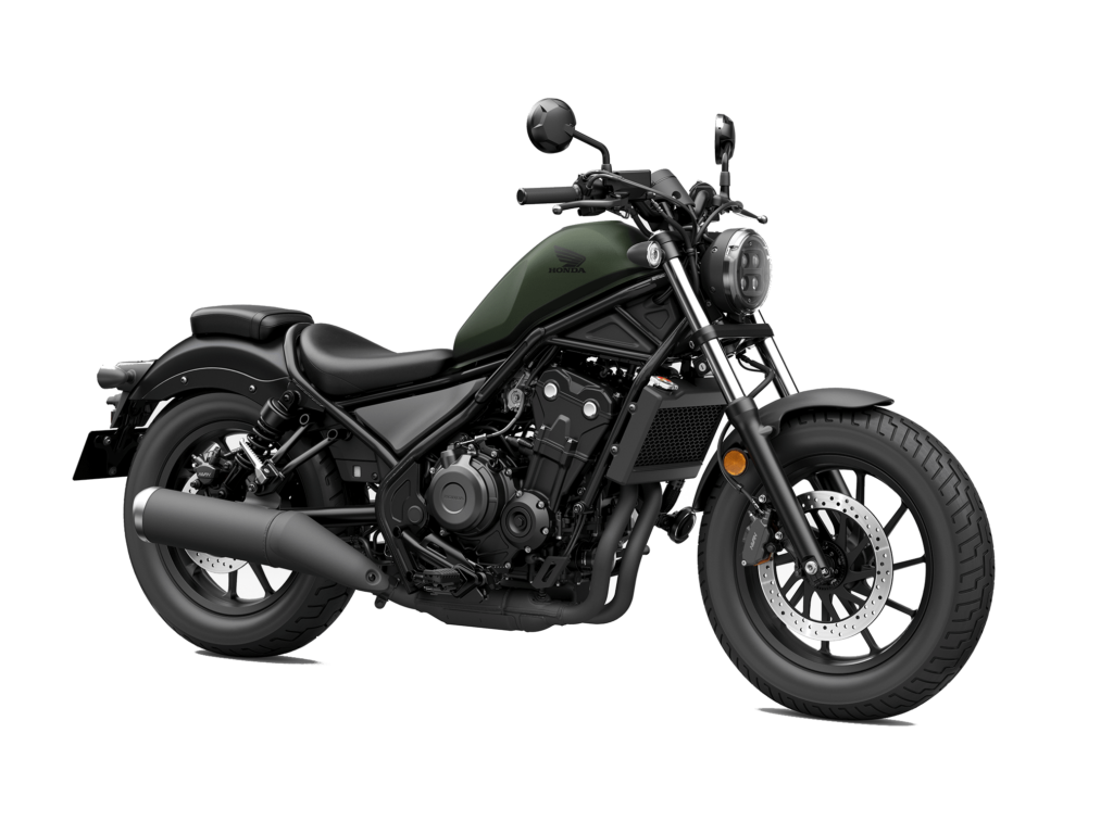 Ein mattgrünes und schwarzes Cruiser-Motorrad mit rundem Scheinwerfer, niedrigem Sitz, breiten Reifen und freiliegendem Motor wird aus dem rechten vorderen Winkel vor einem weißen Hintergrund präsentiert - entdecken Sie exklusive HONDA DEALZ für dieses atemberaubende Fahrzeug. Rider's Point der Kaltenbach Gruppe. Dein Partner für BMW Motorrad und Honda.