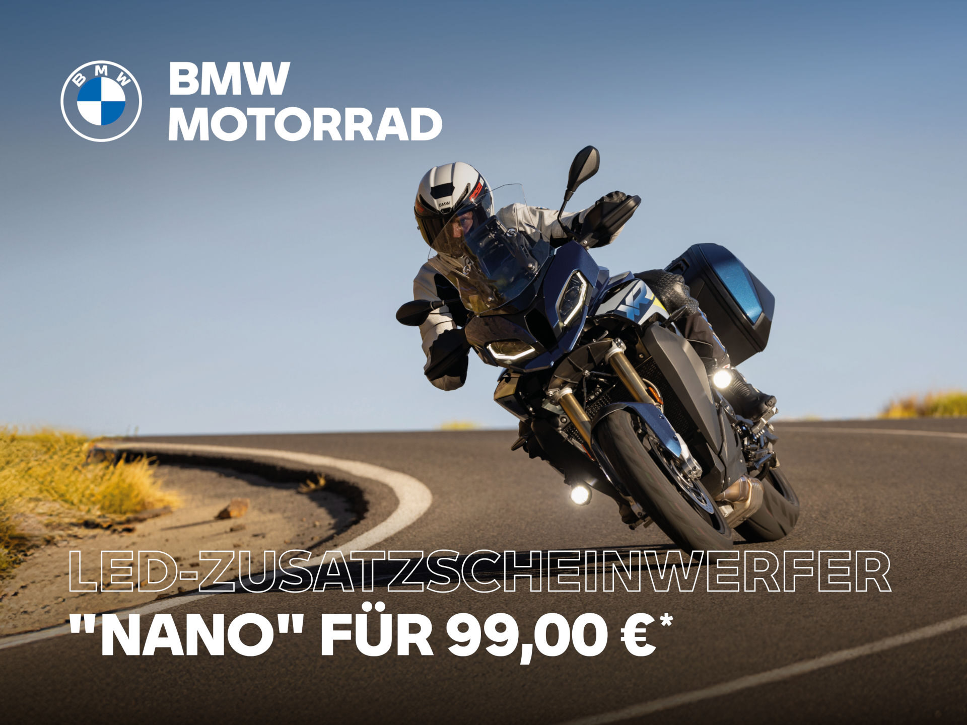 Ein Motorradfahrer fährt mit einem blauen BMW-Motorrad auf einer kurvigen Straße, ausgestattet mit einem Batterieladegerät Plus. Der Text lautet: BMW Motorrad. LED-Zusatzscheinwerfer Nano für 99,00 €* vor dem Hintergrund eines klaren Himmels. Rider's Point der Kaltenbach Gruppe. Dein Partner für BMW Motorrad und Honda.