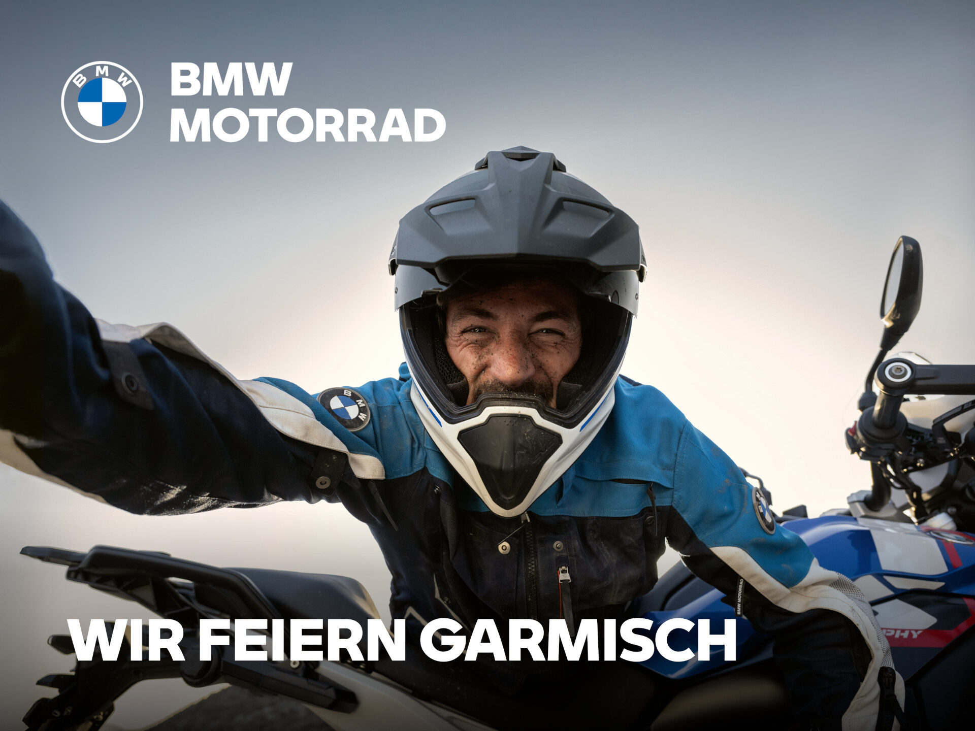 Ein lächelnder Motorradfahrer in BMW Kleidung macht ein Selfie neben einem Motorrad, mit dem BMW Motorrad Logo und dem Text WIR FEIERN GARMISCH auf dem Bild, der die exklusive Saisonstart-Rabatt-Aktion hervorhebt. Rider's Point der Kaltenbach Gruppe. Dein Partner für BMW Motorrad und Honda.