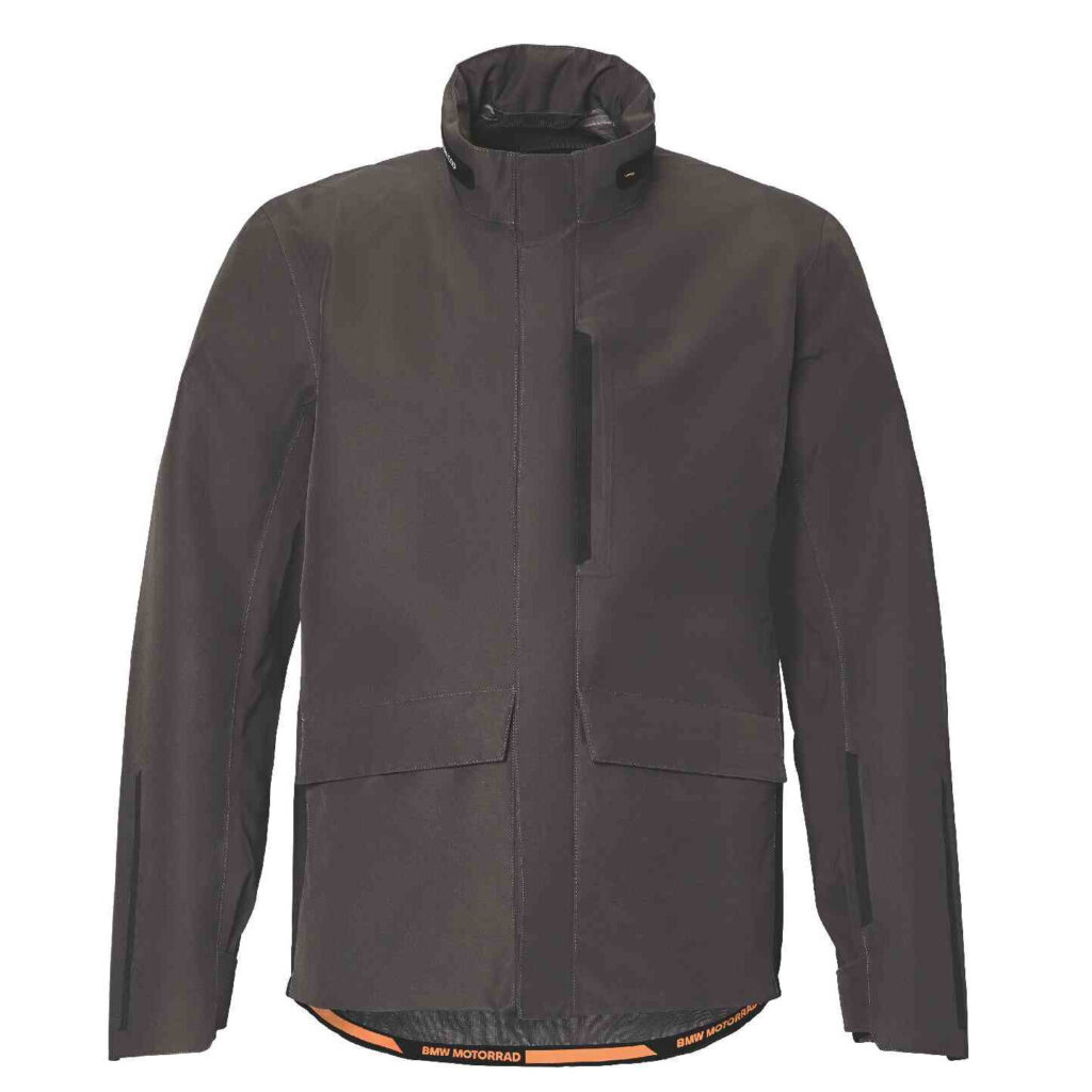 Eine dunkle, langärmelige Motorradjacke mit hohem Kragen, Frontreißverschluss, zwei Fronttaschen und einem sichtbaren orangefarbenen Futter am unteren Rand mit der Aufschrift BMW MOTORRAD. Jetzt als BMW Motorrad Fahrerausstattung reduziert erhältlich. Rider's Point der Kaltenbach Gruppe. Dein Partner für BMW Motorrad und Honda.