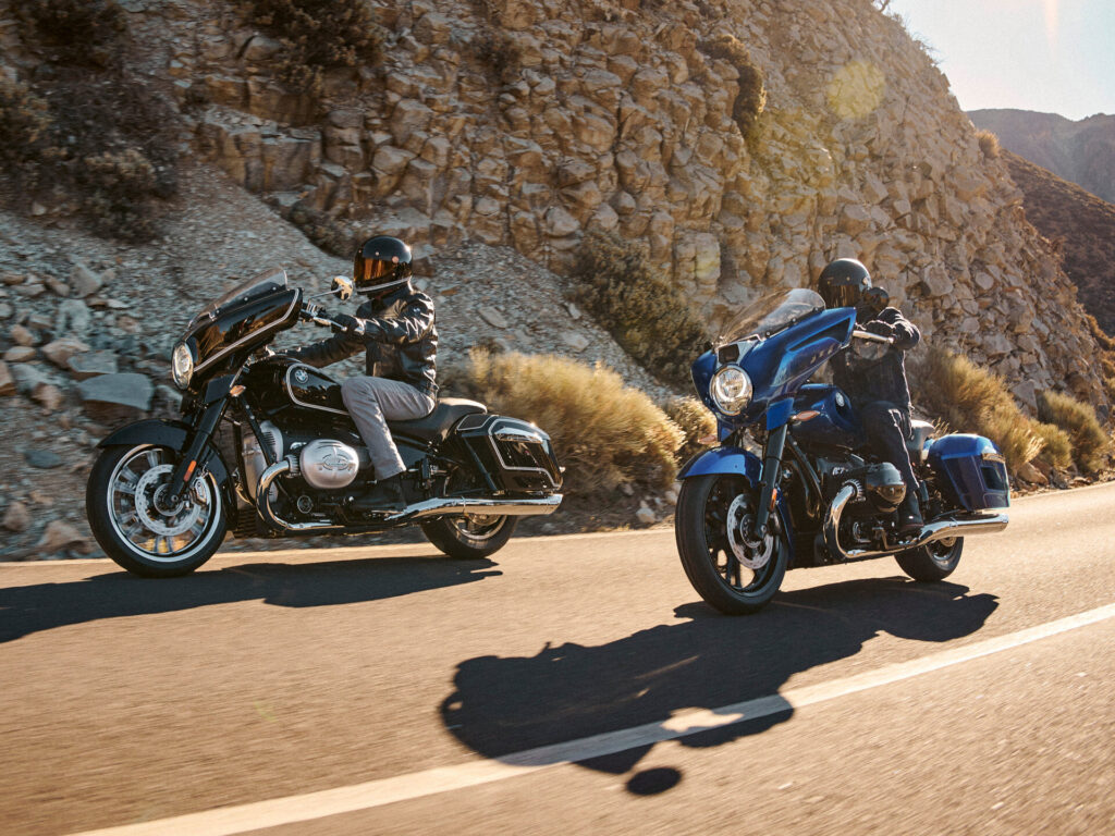 Zwei Personen mit Helmen und Jacken fahren auf großen Tourenmotorrädern über eine sonnenbeschienene Bergstraße und präsentieren ihren Fahrstil vor felsigen Hügeln und trockenem Gebüsch - eine ideale Szene für das Saisonfinale 2025. Rider's Point der Kaltenbach Gruppe. Dein Partner für BMW Motorrad und Honda.