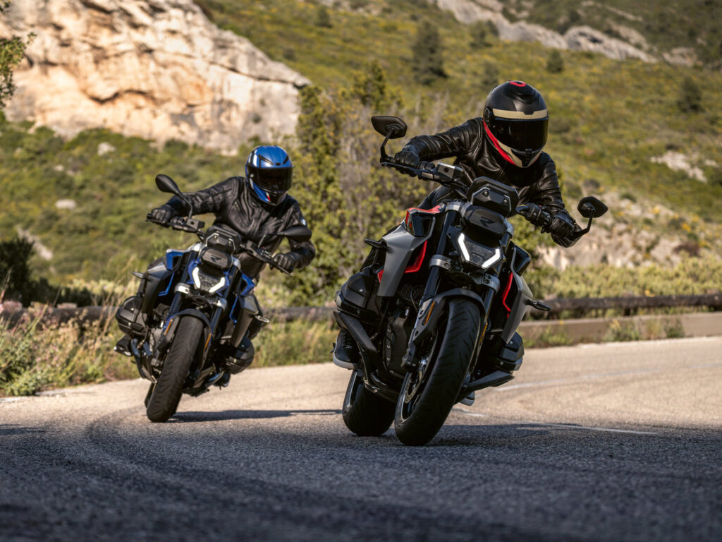 Zwei Motorradfahrer mit Helmen und schwarzen Jacken biegen auf einer Bergstraße in eine Kurve ein und präsentieren ihren Fahrstil inmitten von Grün und felsigen Klippen - eine aufregende Fahrt im Vorfeld des Saisonfinales 2025. Rider's Point der Kaltenbach Gruppe. Dein Partner für BMW Motorrad und Honda.