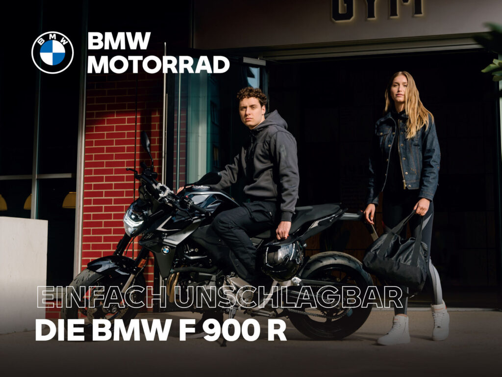 Ein Mann sitzt auf einem schwarzen BMW F 900 R Motorrad vor einem Gebäude, während eine Frau mit einer großen Tasche neben ihm steht. Der Text lautet: "BMW Motorrad. Einfach unschlagbar. Die BMW F 900 R." Entdecke jetzt die BMW F 800 GS Sonderaktion!. Rider's Point der Kaltenbach Gruppe. Dein Partner für BMW Motorrad und Honda.