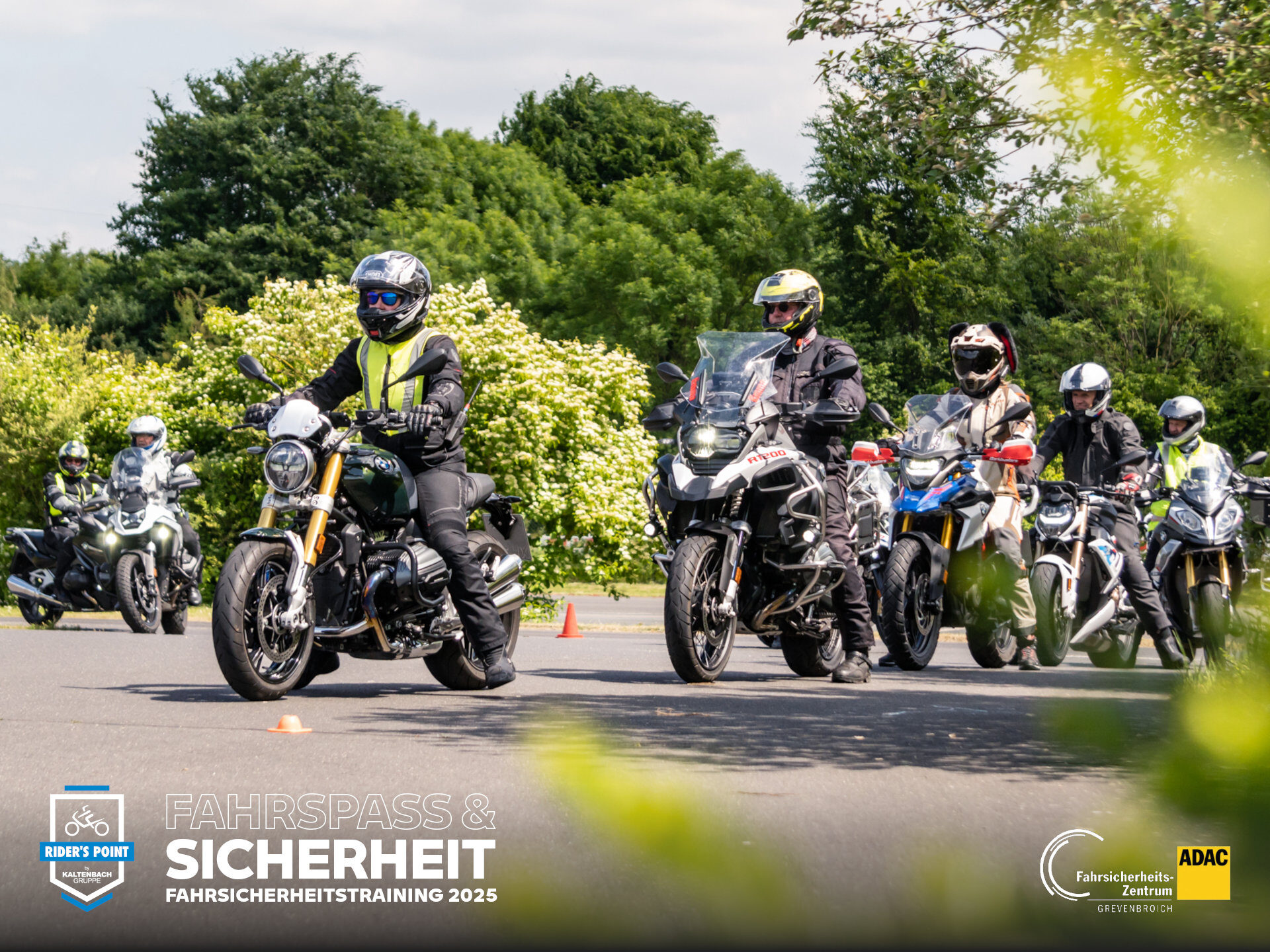 Eine Gruppe von Motorradfahrern mit Helmen und Sicherheitsausrüstung nimmt an einem Fahrsicherheitstraining im Freien teil, mit grünen Bäumen im Hintergrund und Verkehrskegeln auf dem Bürgersteig. Im Vordergrund sind Logos und deutscher Text zu sehen. Rider's Point der Kaltenbach Gruppe. Dein Partner für BMW Motorrad und Honda.